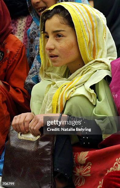 An Afghan schoolgirl cluthes her purse as she recites the letters of the Dari alphabet at the Amir Dost Mohammad Khan Secondary School on the first...
