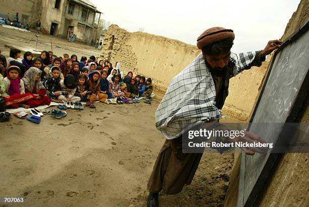 Young children at the Amir Dost Mohammad Khan school in Kabul, Afghanistan watch March 23, 2002 as their teacher writes out an exercise on the first...