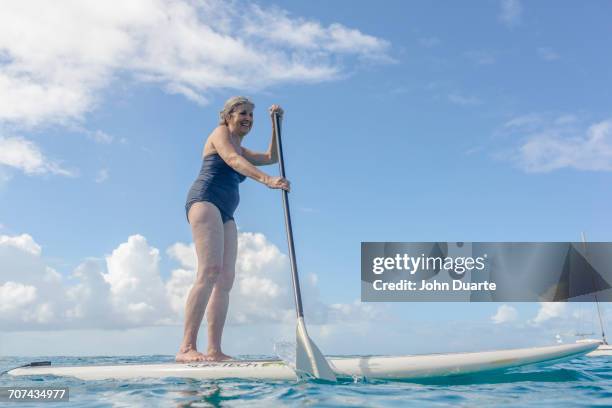 caucasian woman standing on paddle board on ocean - hot women on boats ストックフォトと画像