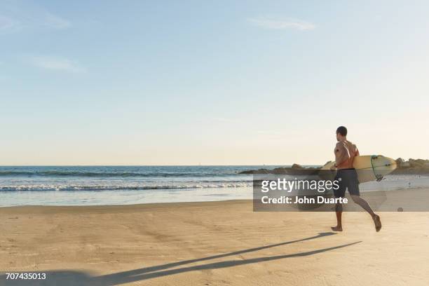 mixed race man running with surfboard on beach - beach la stock pictures, royalty-free photos & images