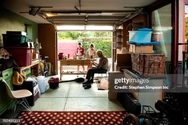grandfather watching granddaughters building birdhouse in garage - old garage at home stock pictures, royalty-free photos & images