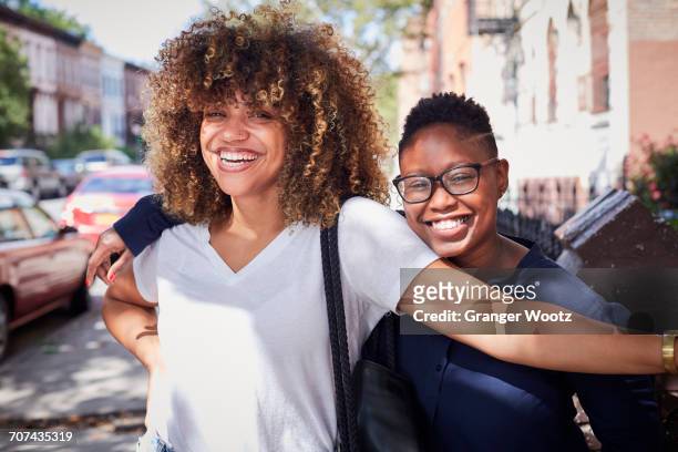 Portrait of Black women hugging on city sidewalk