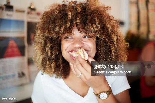 black woman biting sandwich - frau locken beauty nicht draußen stock-fotos und bilder