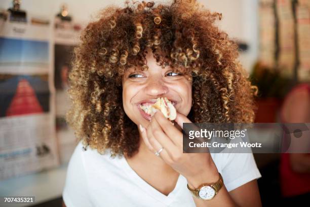black woman biting sandwich - placer fotografías e imágenes de stock