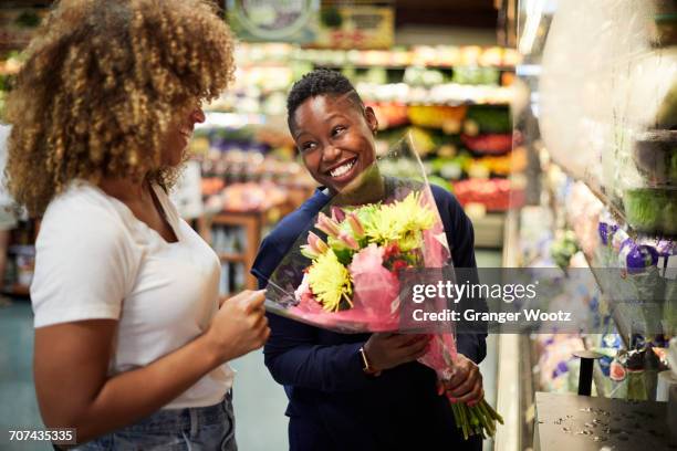 black woman showing bouquet to girlfriend in store - i love new york foto e immagini stock
