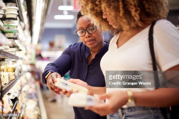 black women examining cheese in grocery store - dairy product stock photos et images de collection