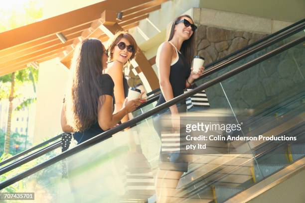 glamorous friends riding escalator in shopping mall - escalator side view stock pictures, royalty-free photos & images