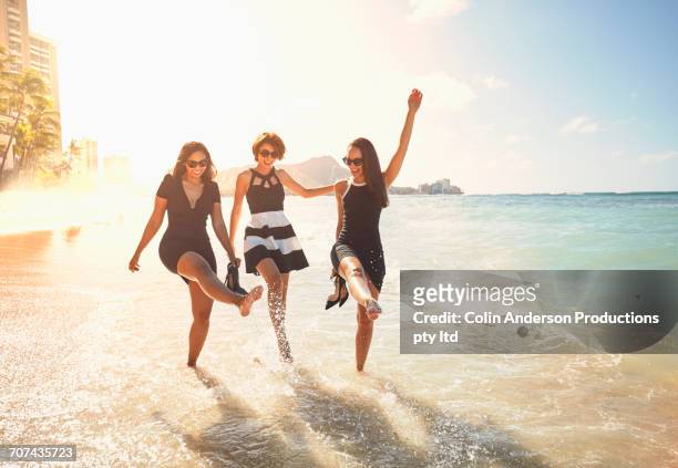glamorous friends splashing on ocean waves - hawaii fun stock-fotos und bilder