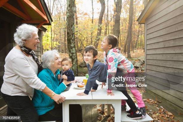 Grandmothers playing with grandchildren at breakfast table outdoors