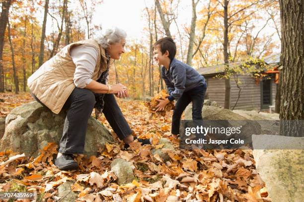 grandmother and grandson playing with autumn leaves - alte und junge lesbische frauen stock-fotos und bilder