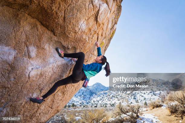 mixed race girl climbing rock - girl side view stock-fotos und bilder