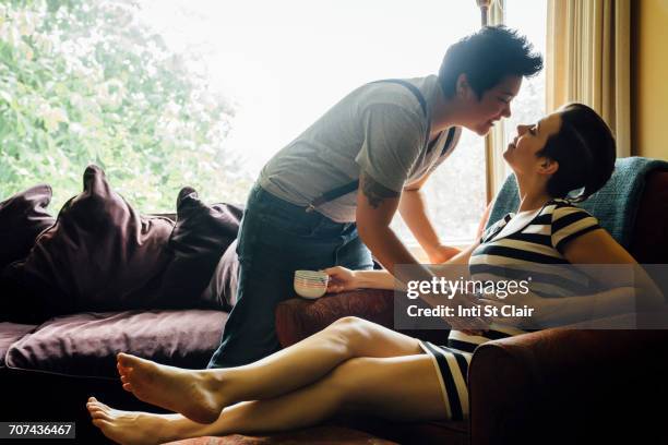 pregnant lesbian couple kissing in livingroom - asian lesbians kiss stock pictures, royalty-free photos & images