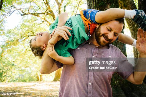 Caucasian father playing with son on shoulder