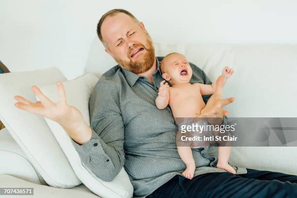 portrait of crying father holding crying baby daughter - baby crying photos et images de collection