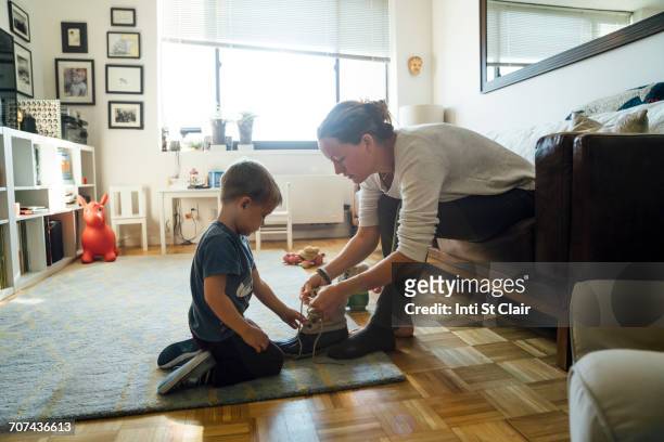 mother teaching son to tie shoelace - cordón de zapato fotografías e imágenes de stock