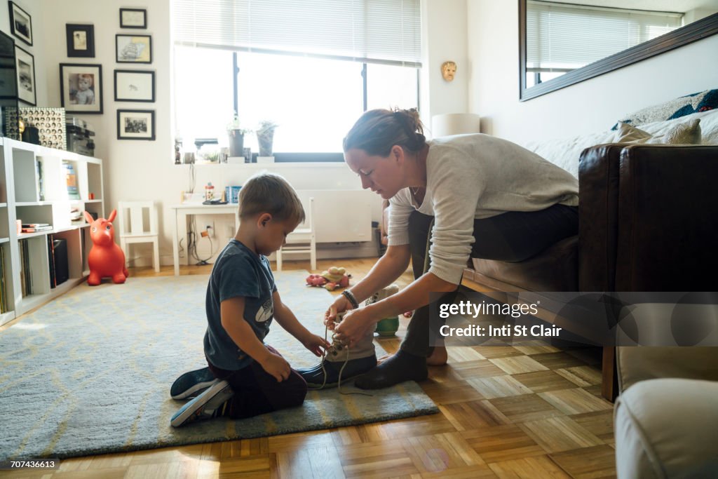 Mother teaching son to tie shoelace