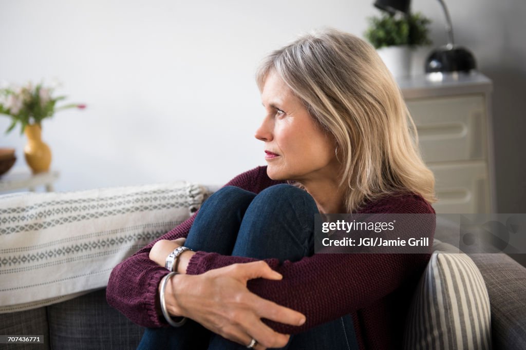 Worrying Caucasian woman hugging legs