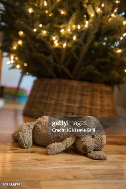 teddy bear laying on floor near christmas tree - stuffed toy stock pictures, royalty-free photos & images