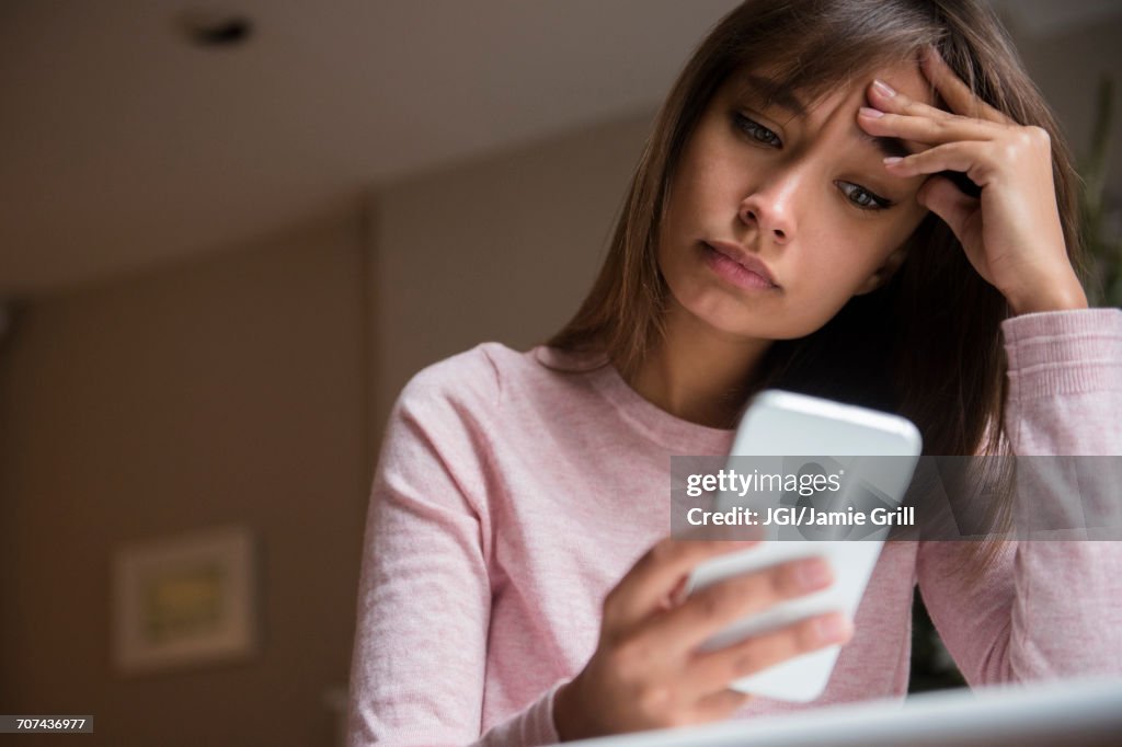 Frustrated Mixed Race woman texting on cell phone