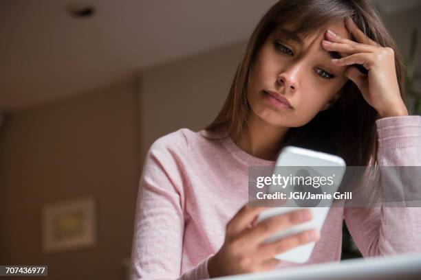 frustrated mixed race woman texting on cell phone - answering stockfoto's en -beelden