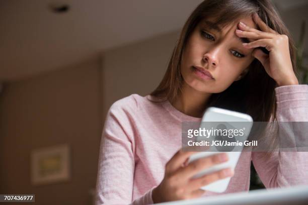 frustrated mixed race woman texting on cell phone - dificuldades em relações imagens e fotografias de stock