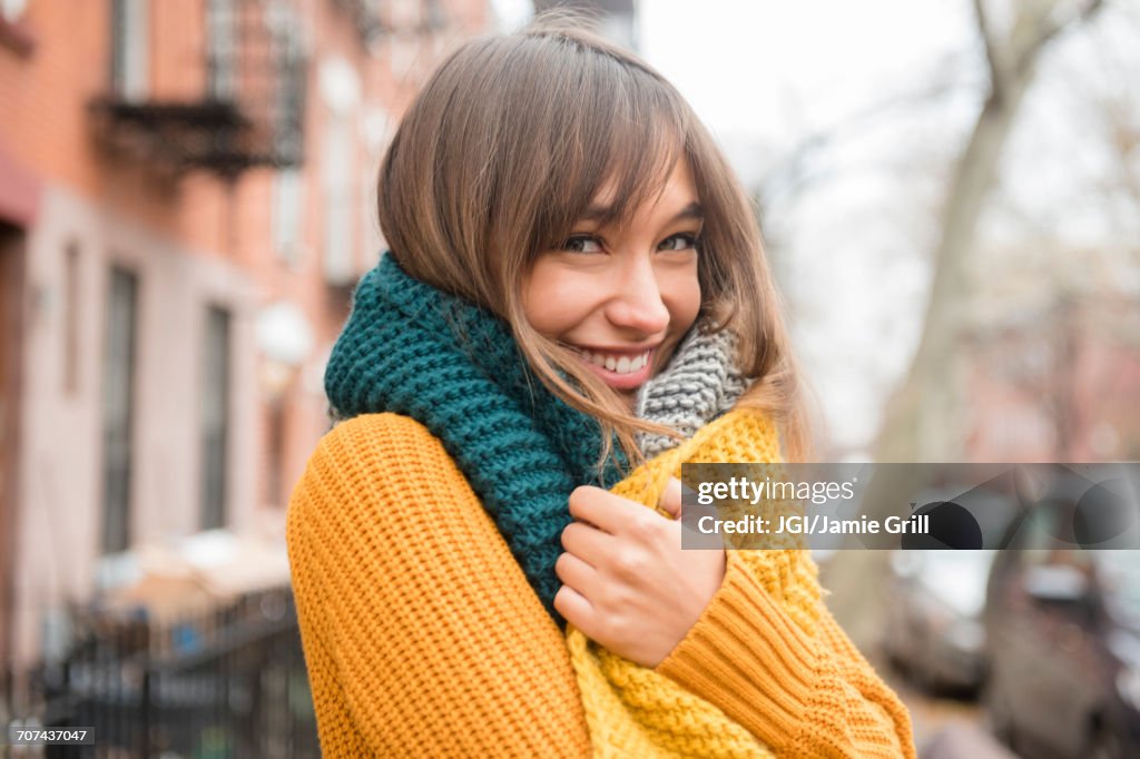 Portrait of smiling Mixed Race woman wearing scarf in city