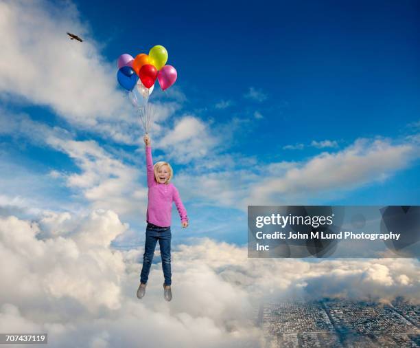 Caucasian Girl Holding Helium Balloons Flying In Clouds Over