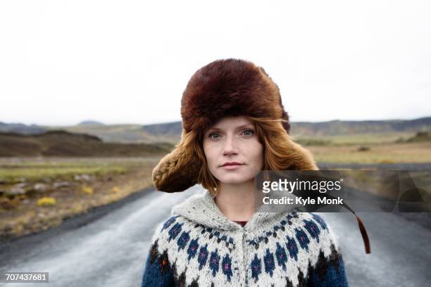 caucasian woman wearing sweater and fur hat in middle of road - 毛皮の帽子 ストックフォトと画像