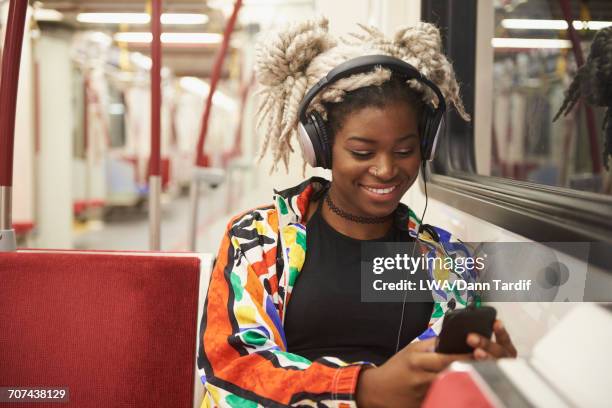 black woman listening to cell phone with headphones on subway - toronto people stock pictures, royalty-free photos & images