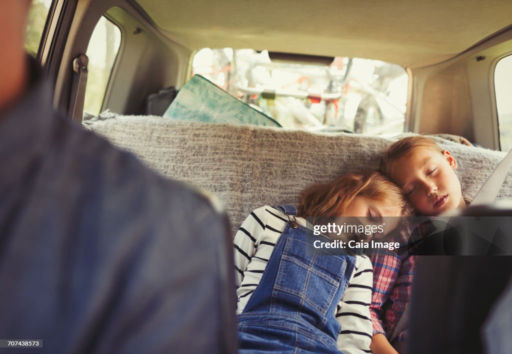 Tired sisters sleeping in back seat of car