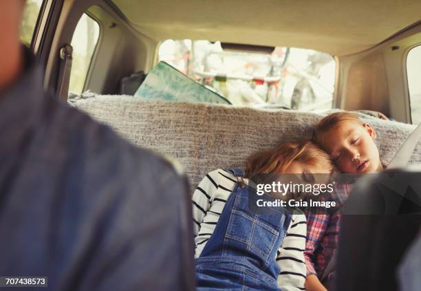 tired sisters sleeping in back seat of car - kid car seat stock pictures, royalty-free photos & images