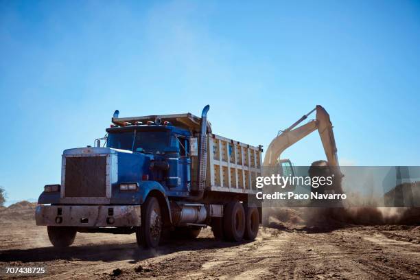truck near digger in dirt field - camión de descarga fotografías e imágenes de stock