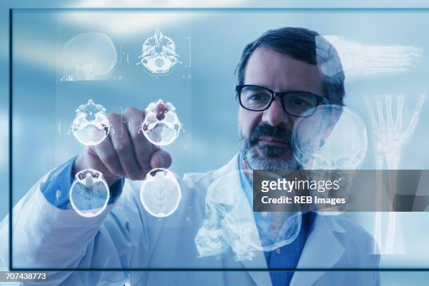 hispanic doctor examining x-rays on virtual screen - future health care fotografías e imágenes de stock