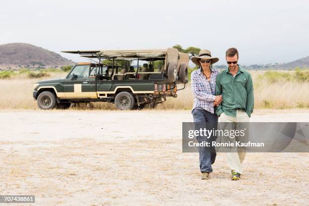 caucasian couple walking arm in arm near truck - kenya safari stock pictures, royalty-free photos & images
