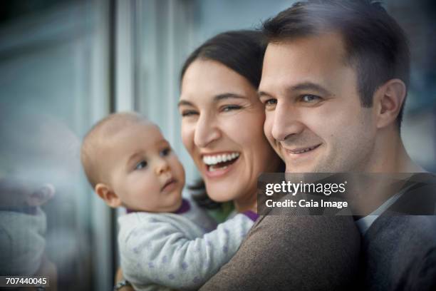 smiling happy parents holding baby daughter - baby father hug side stock pictures, royalty-free photos & images