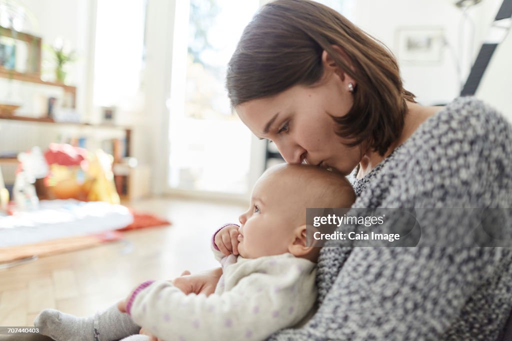 Mother kissing baby daughter on the head