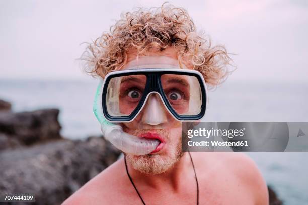 portrait of young man with diving goggles and snorkel pulling funny faces - dykmask bildbanksfoton och bilder