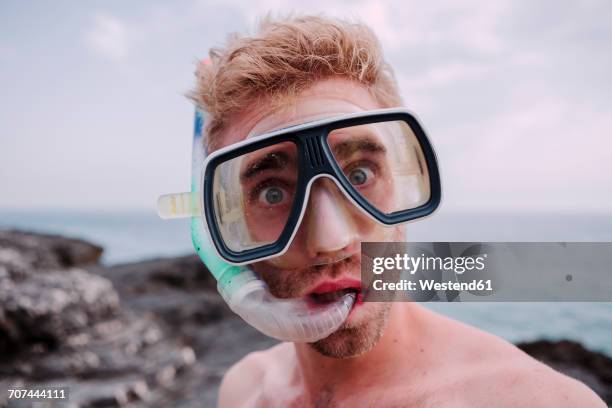 portrait of young man with diving goggles and snorkel pulling funny faces - asking face stock pictures, royalty-free photos & images