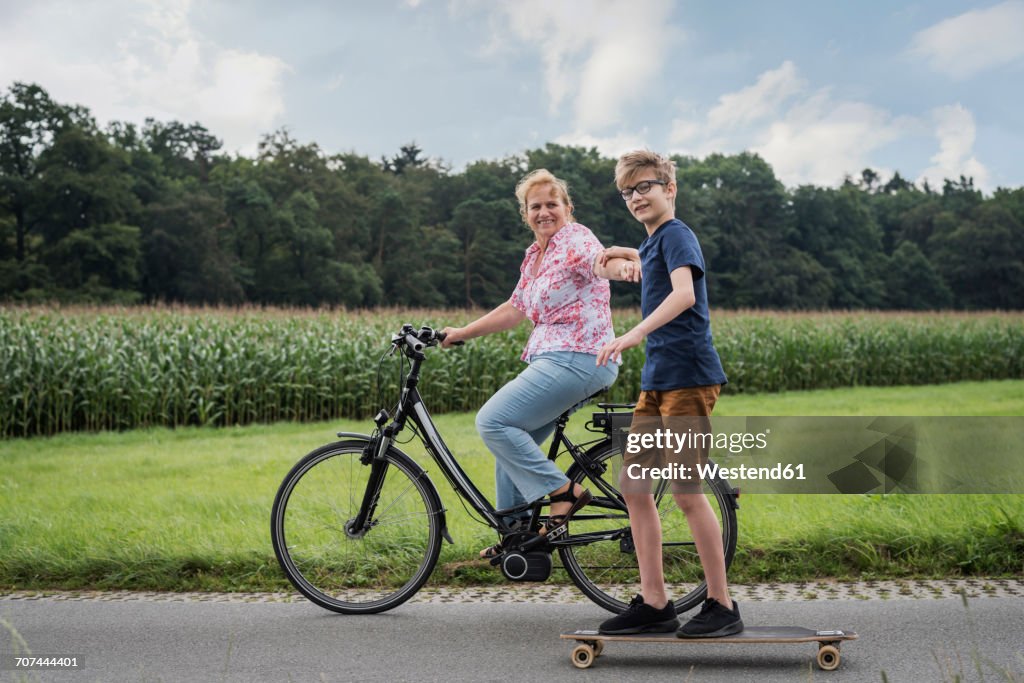 Grandson and grandmother riding bicycle and skateboard together