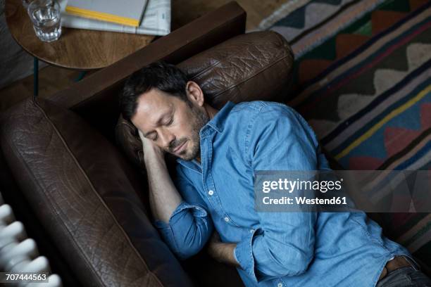 man lying on couch, taking a nap - napping stock pictures, royalty-free photos & images