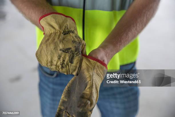 construction worker putting on protective gloves - protective workwear for manual worker stockfoto's en -beelden