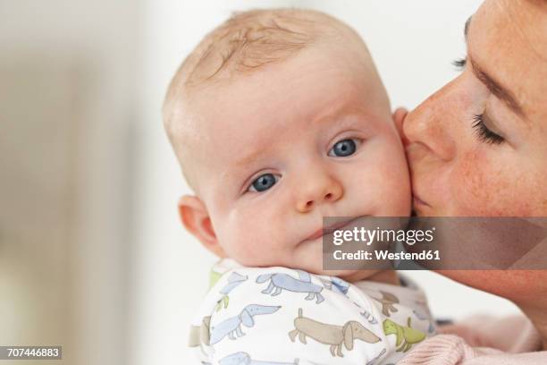 close-up of mother kissing baby - babyface stock-fotos und bilder