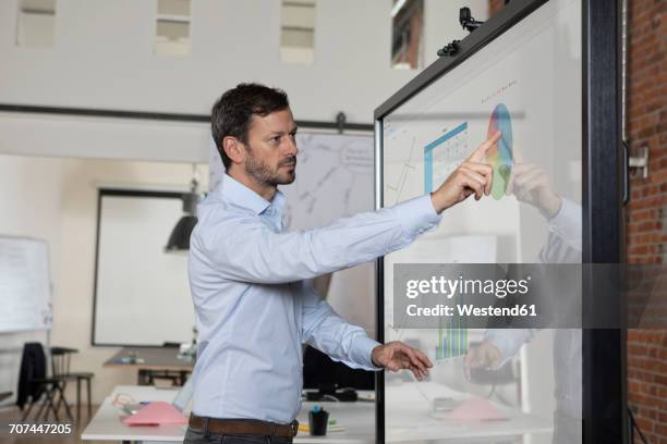 businessman handling graphs on screen in office - interactive stock-fotos und bilder