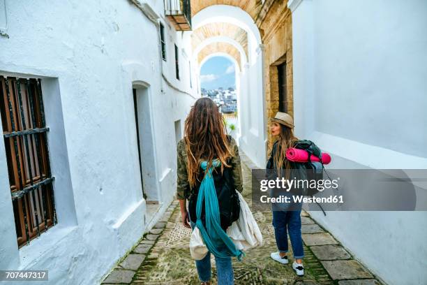 spain, andalusia, vejer de la frontera, two young women walking in the alley el callejon de las monjas - vejer de la frontera stockfoto's en -beelden
