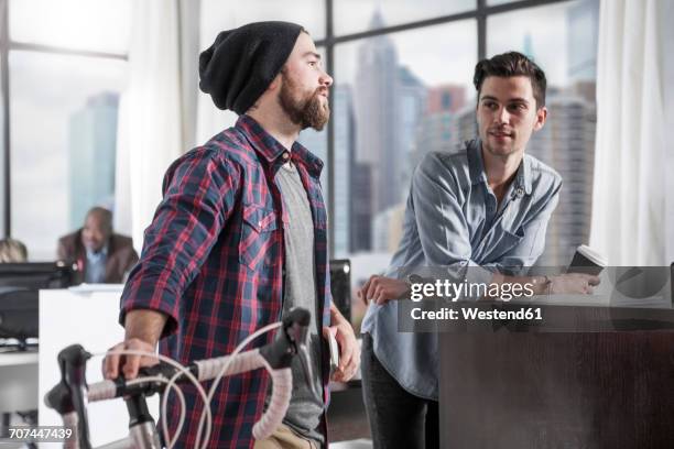 casual man with bike in modern office - funky office stock pictures, royalty-free photos & images