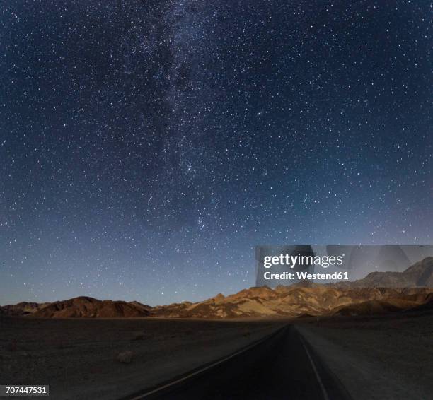 usa, california, death valley, night shot with stars and milky way over road to zabriskie point - zabriskie point stock pictures, royalty-free photos & images