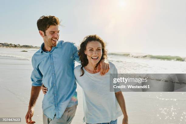 laughing couple on the beach - smiling controluce foto e immagini stock