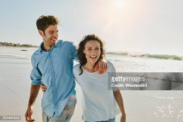 laughing couple on the beach - woman happy walk imagens e fotografias de stock