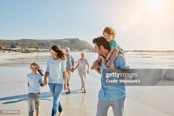 three generations family strolling on the beach - multigenerational family beach stock pictures, royalty-free photos & images