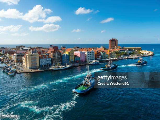 curacao, willemstad, punda, tugboats and colorful houses at waterfront promenade - willemstad stockfoto's en -beelden